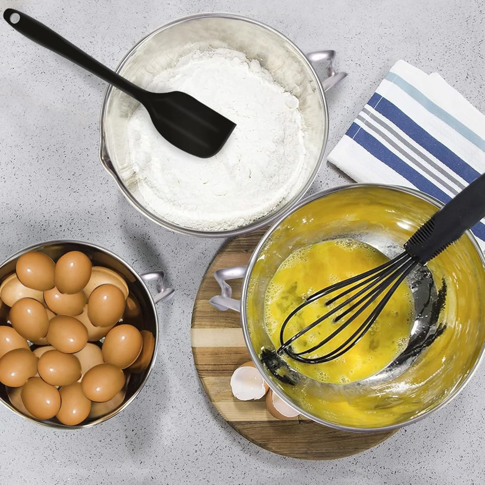 Eggs, flour and whisked yolks in stainless bowls on a worktop